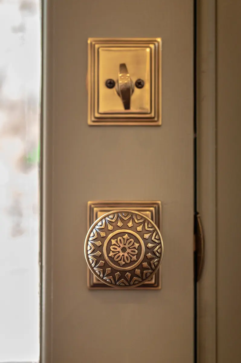 Close-up of ornate brass door knob and lock plate with floral pattern.