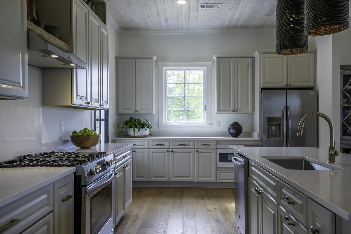 Kitchen with gray cabinetry, marble countertop, stainless steel appliances, and a large window with greenery.