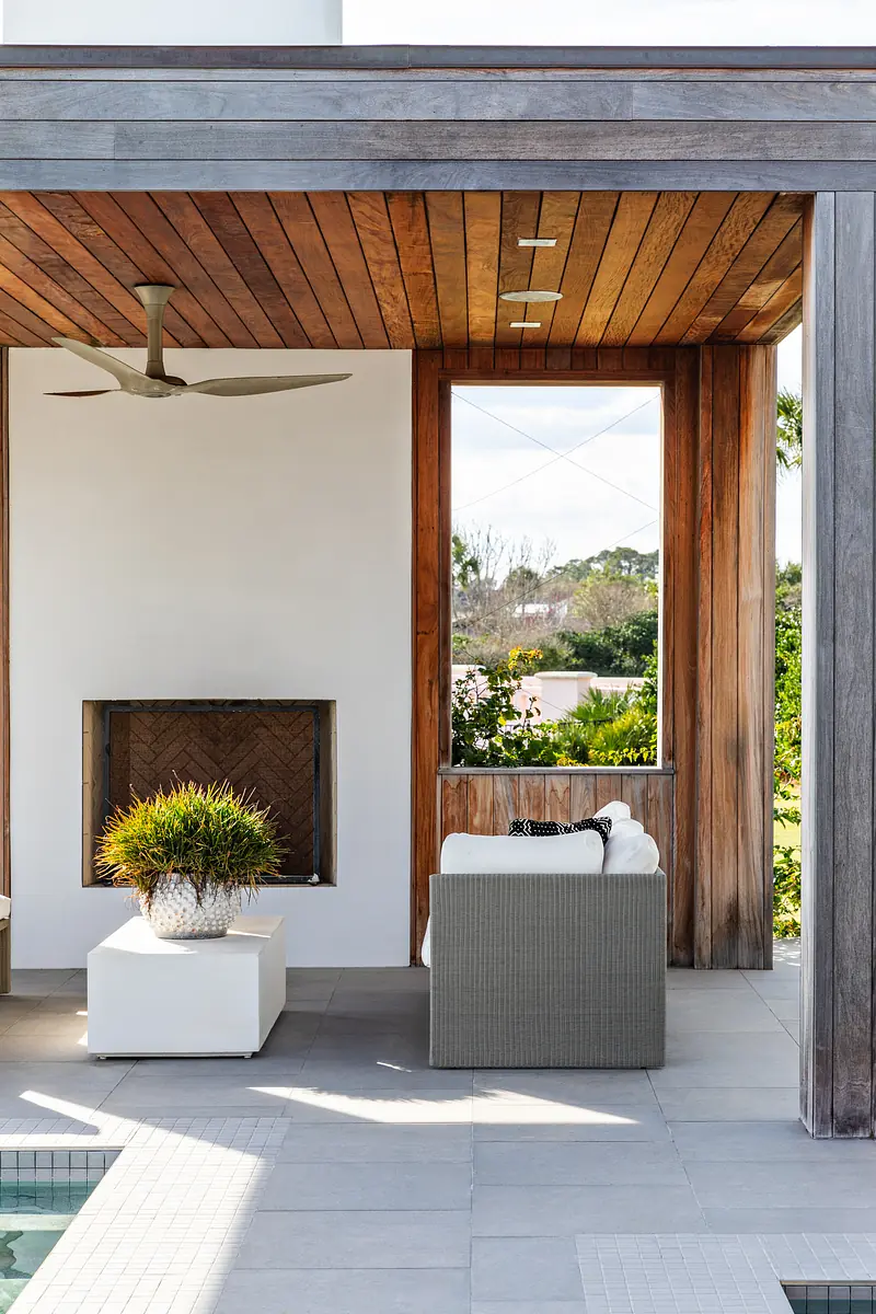Patio with gray wicker sofa, white coffee table, built-in fireplace, wooden ceiling, and large window