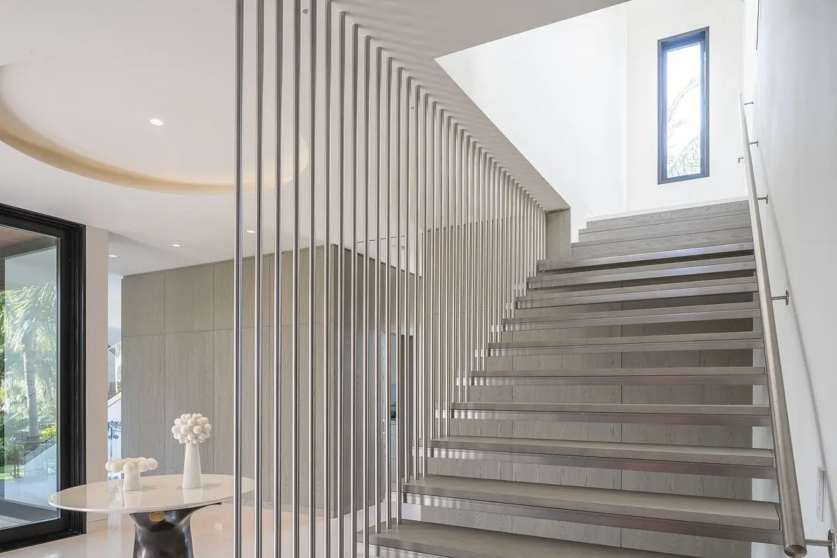 Hallway with staircase, round table, decorative object, large windows, and flat panel details on white walls.