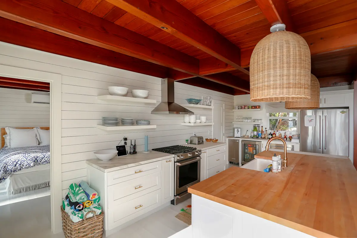 Kitchen with white cabinetry, stainless steel appliances, wood countertop, island, and open shelving for dishware.