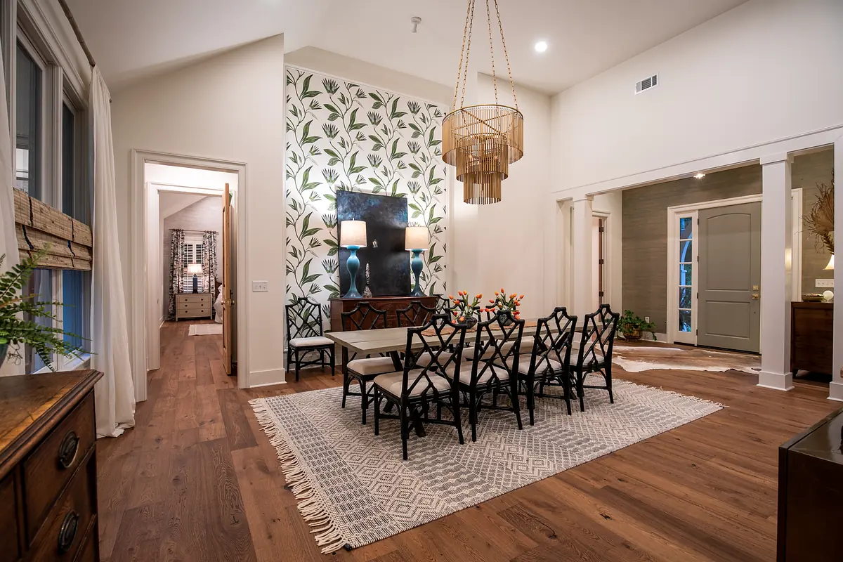 Dining room with rectangular table, black chairs, area rug, floral wall, console table, and pendant light.