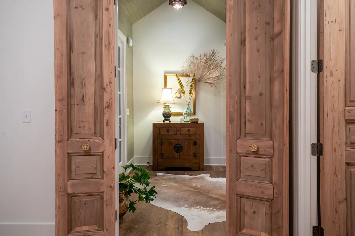Foyer with wooden chest, table lamp, decorative vase, mirror, and cowhide rug.