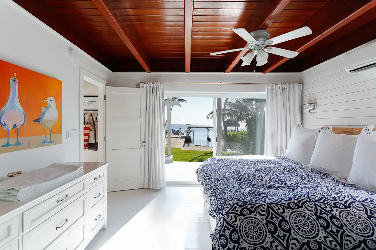 Bedroom with king-sized bed, blue quilt, nightstands, dresser, and large window with an exterior view.