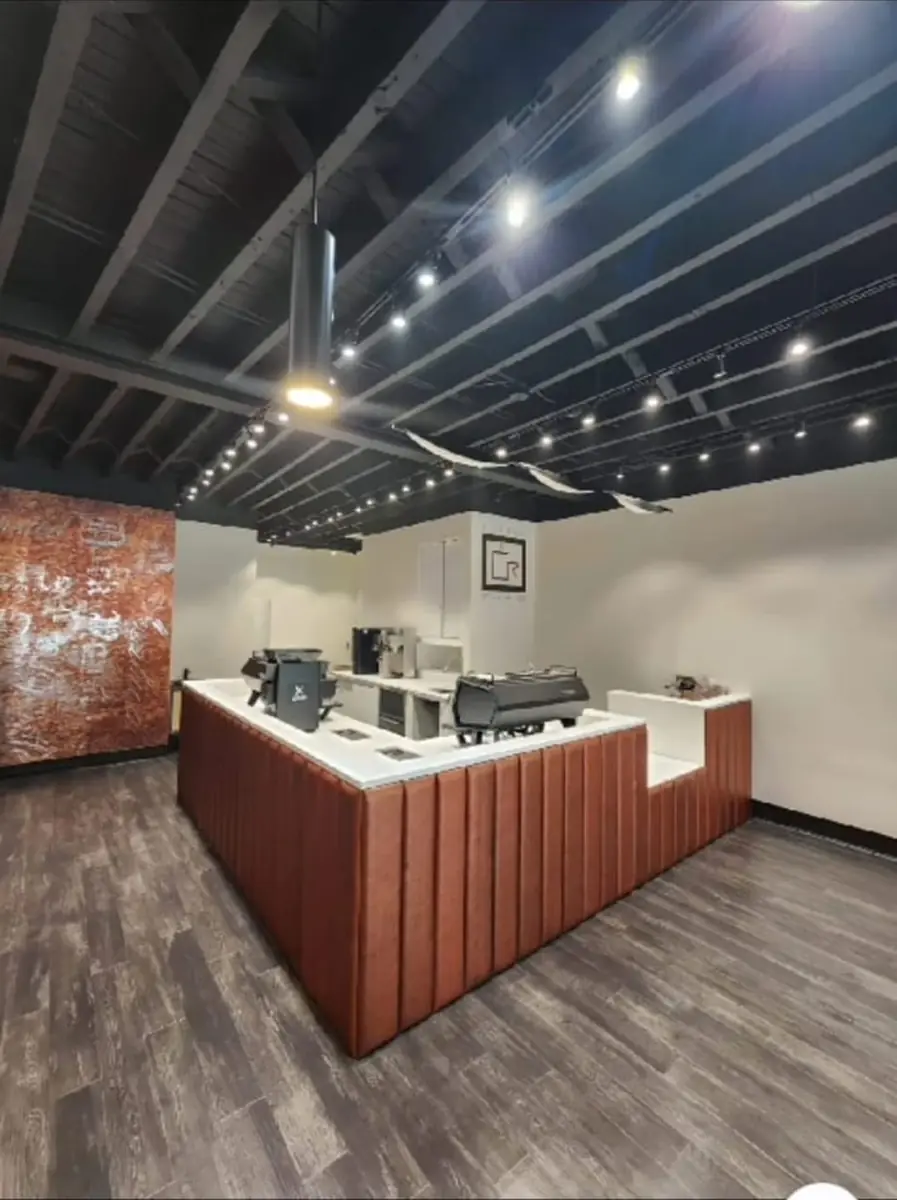 Kitchen with central island, wooden front, white countertops, appliances, and exposed beam ceiling.