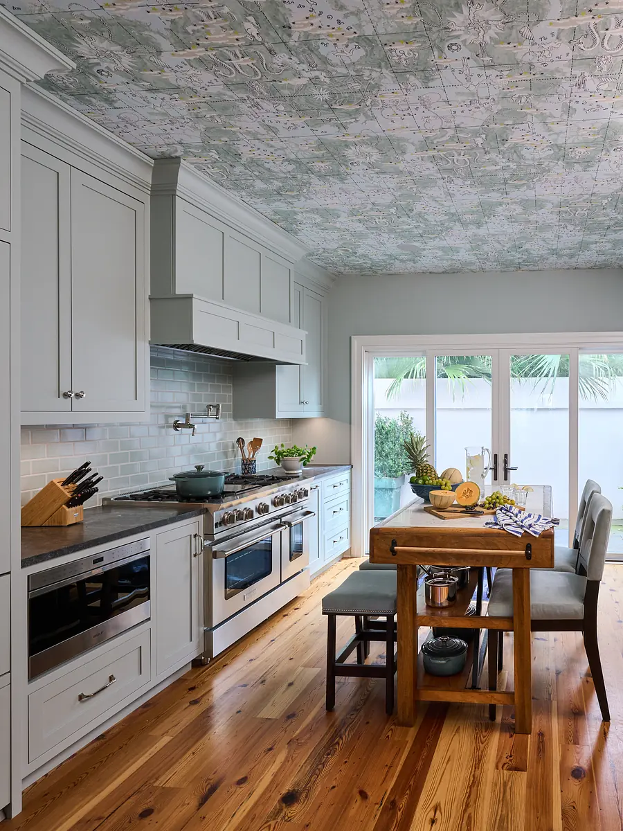 Kitchen with gray cabinetry, stainless steel appliances, wood dining table, and white subway tile backsplash.