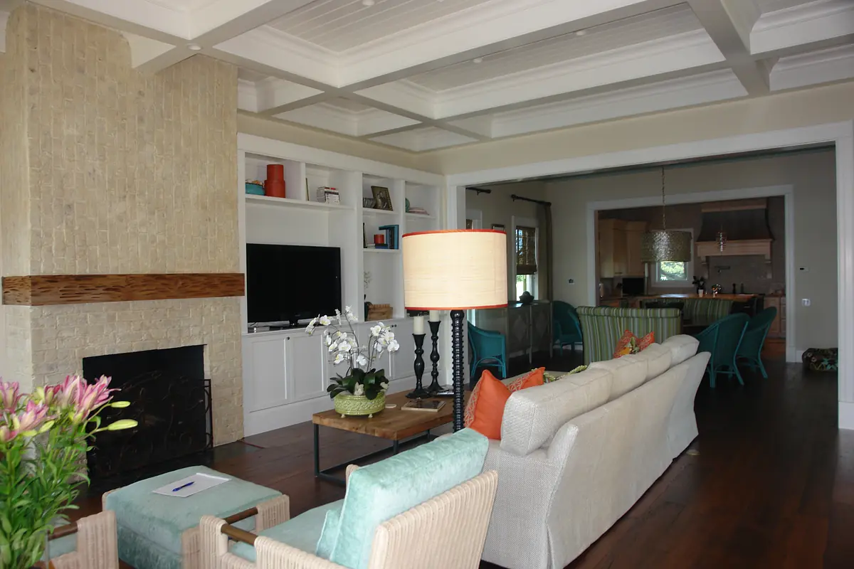 Living room with beige sofa, aqua chairs, built-in shelves, a fireplace, and a coffered ceiling.