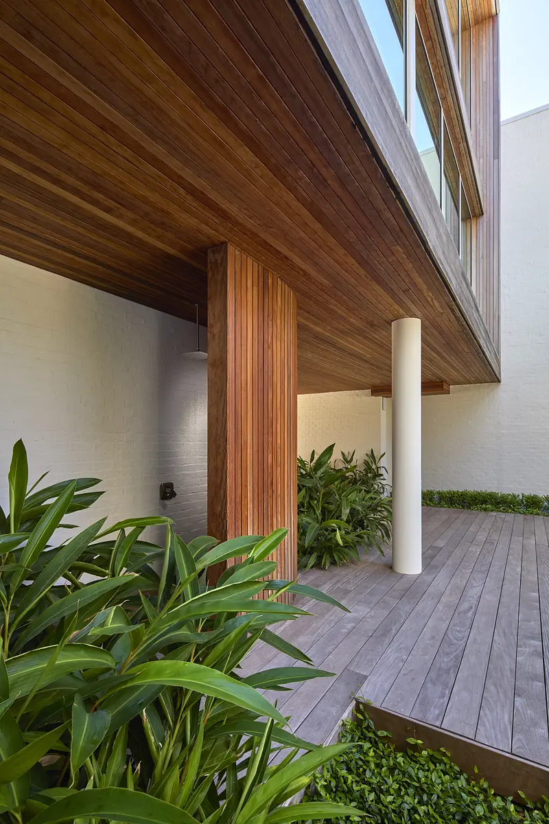 Exterior space with wooden deck, greenery, and vertical wooden post.