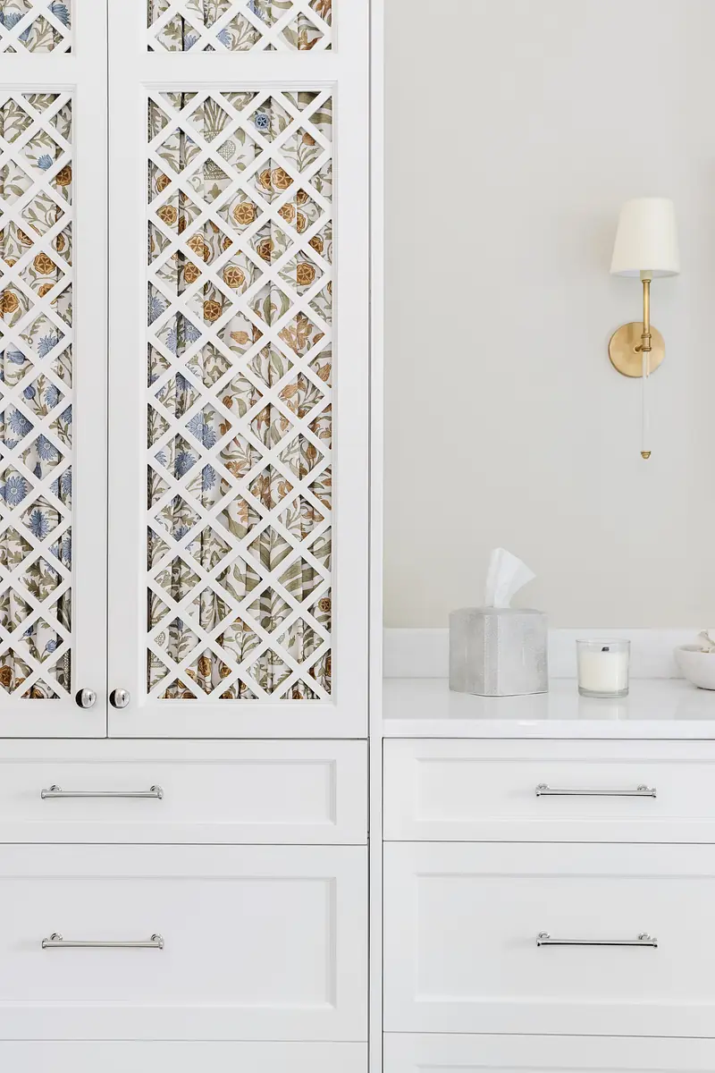 Kitchen with white cabinetry, marble countertop, sconce, and decorative glass pattern.