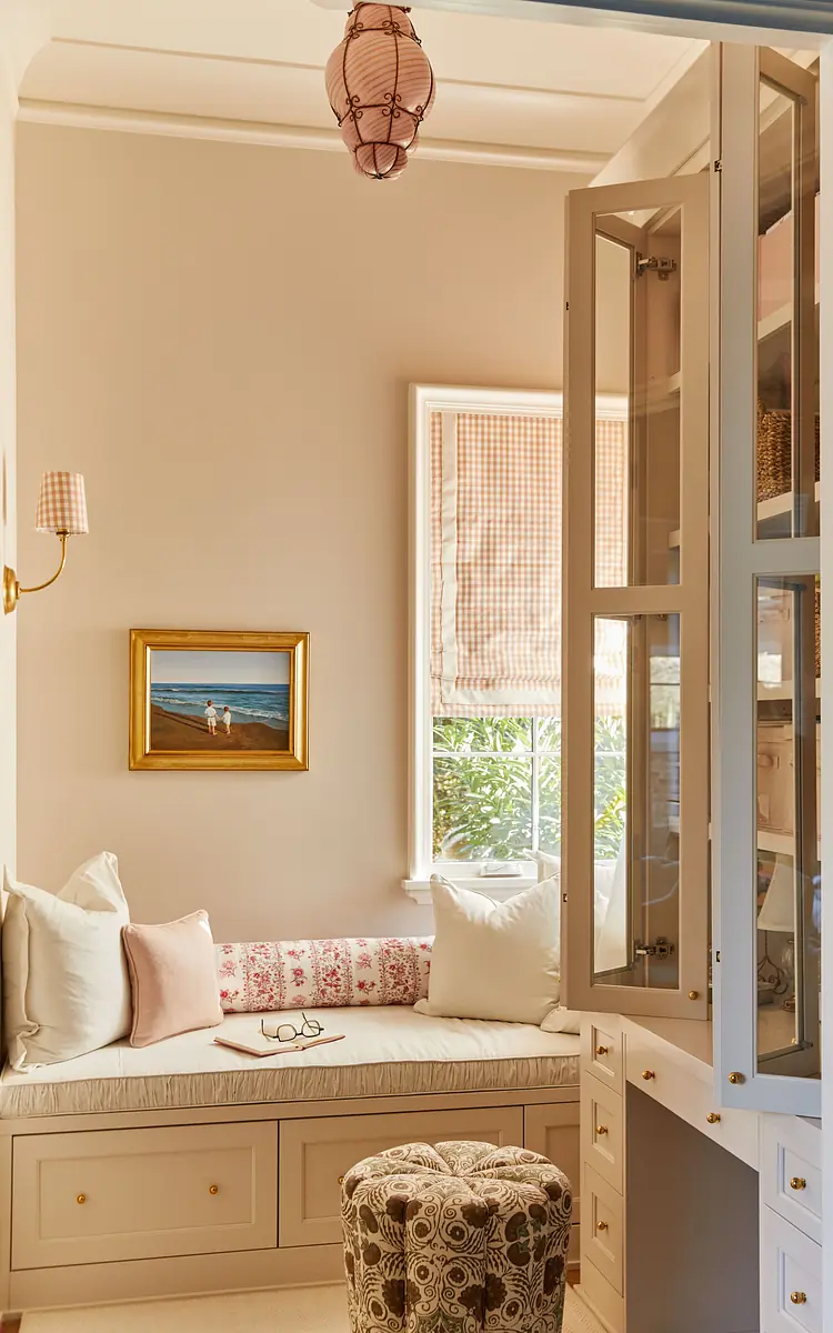Nook with built-in bench, cushions, stool, painting, cabinetry, and window with checkered shade