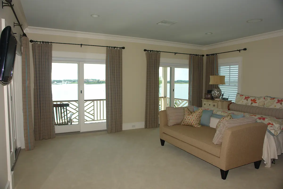 Living room with beige sofa, area rug, curtains, sliding doors, and waterfront view.