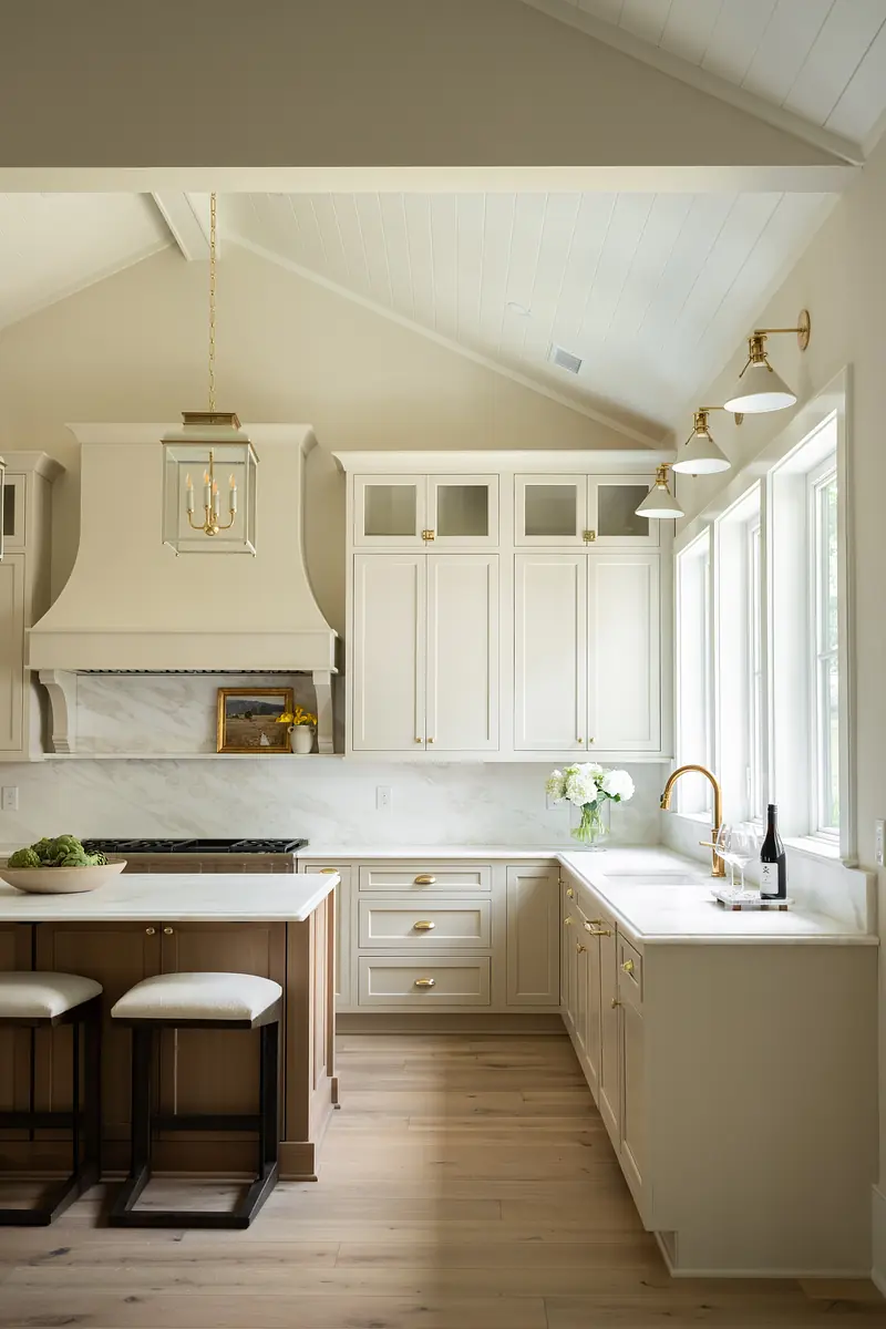 Kitchen with white cabinets, marble countertops, large island, and natural light from windows