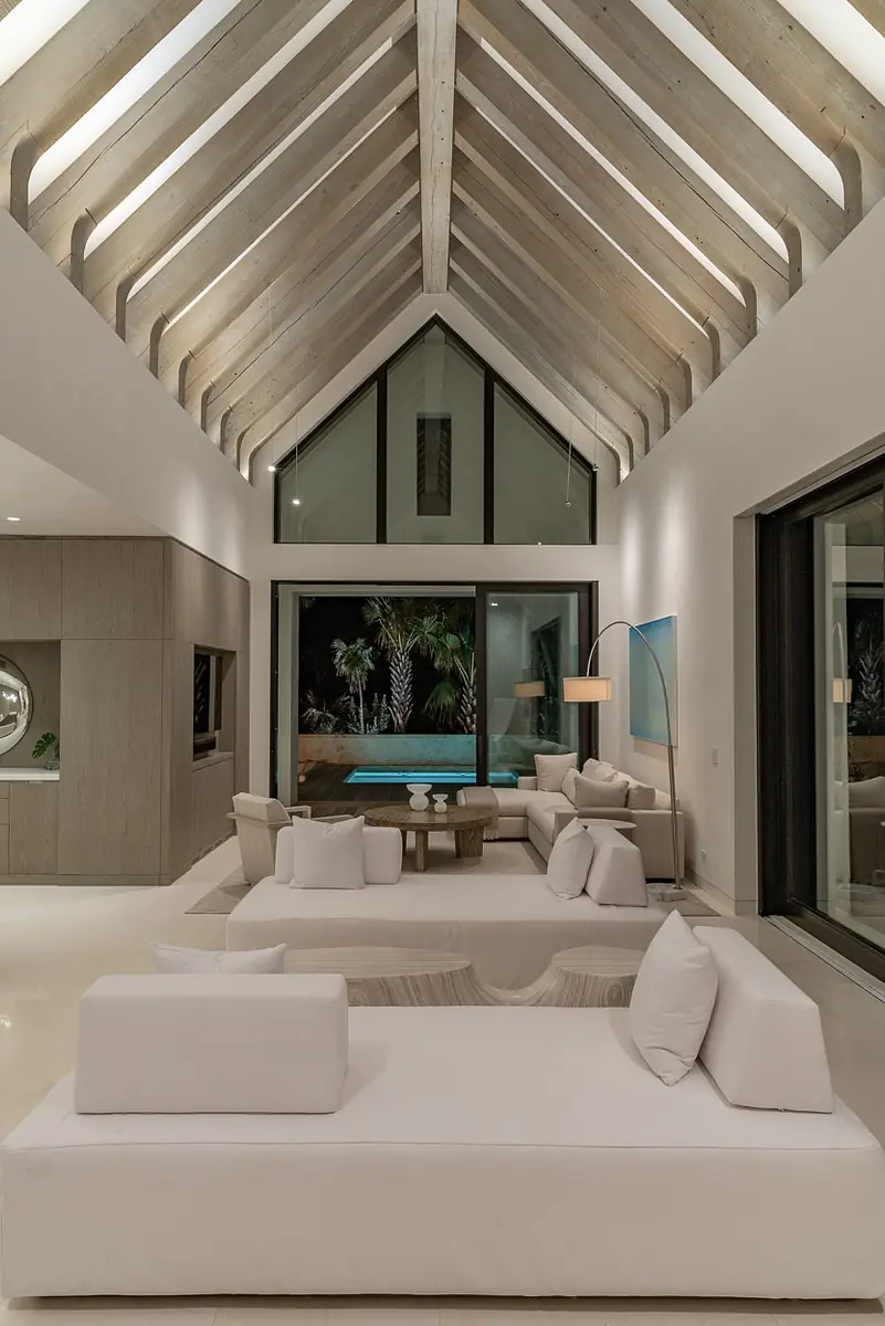 Living room with sectional sofa, coffee table, sliding glass doors, and vaulted ceiling with exposed beams