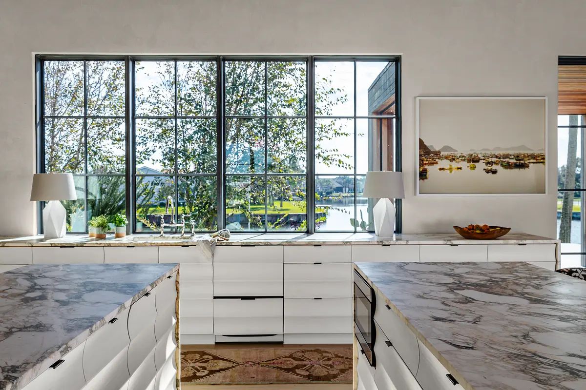 Kitchen with marble islands, white cabinetry, and large window offering outdoor views