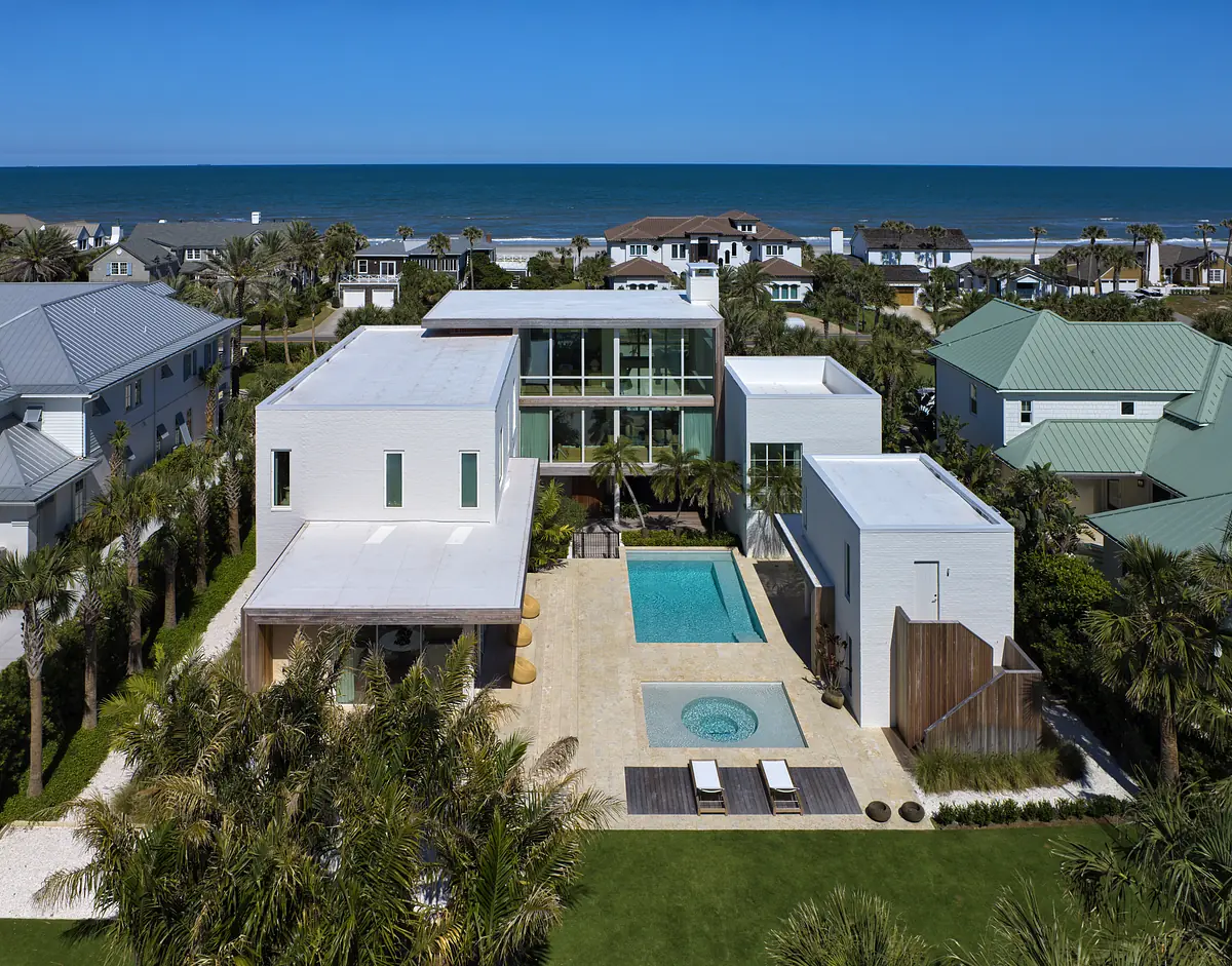 Exterior rear view of modern house with swimming pool, hot tub, wooden deck, palm trees, and landscaped yard