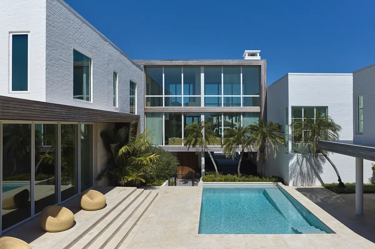 Exterior area with swimming pool, terrace, tropical plants, and modern building with large glass windows