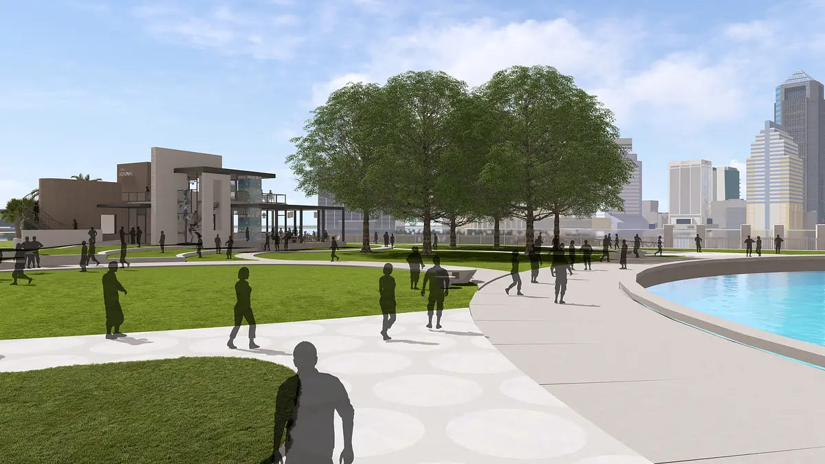 Outdoor park with grassy area, walking paths, trees, water, and a background building.