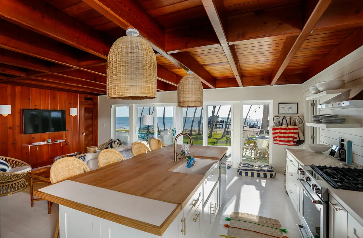 Kitchen with central island, white cabinets, woven pendant lights, and large windows with views.