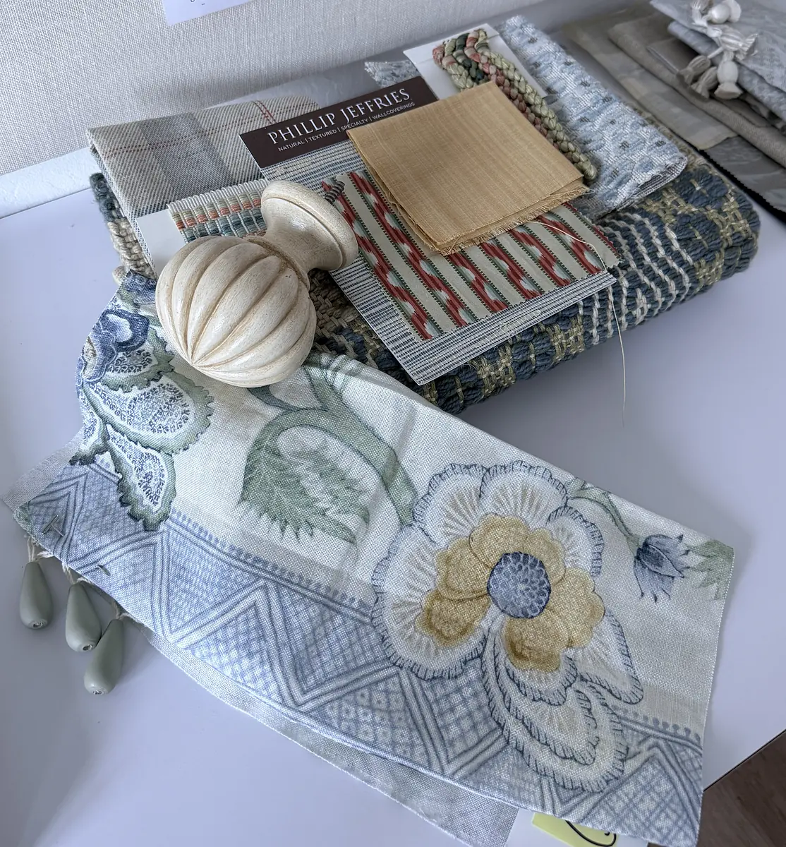 Collection of fabric swatches with floral and geometric patterns, and a decorative wooden knob.