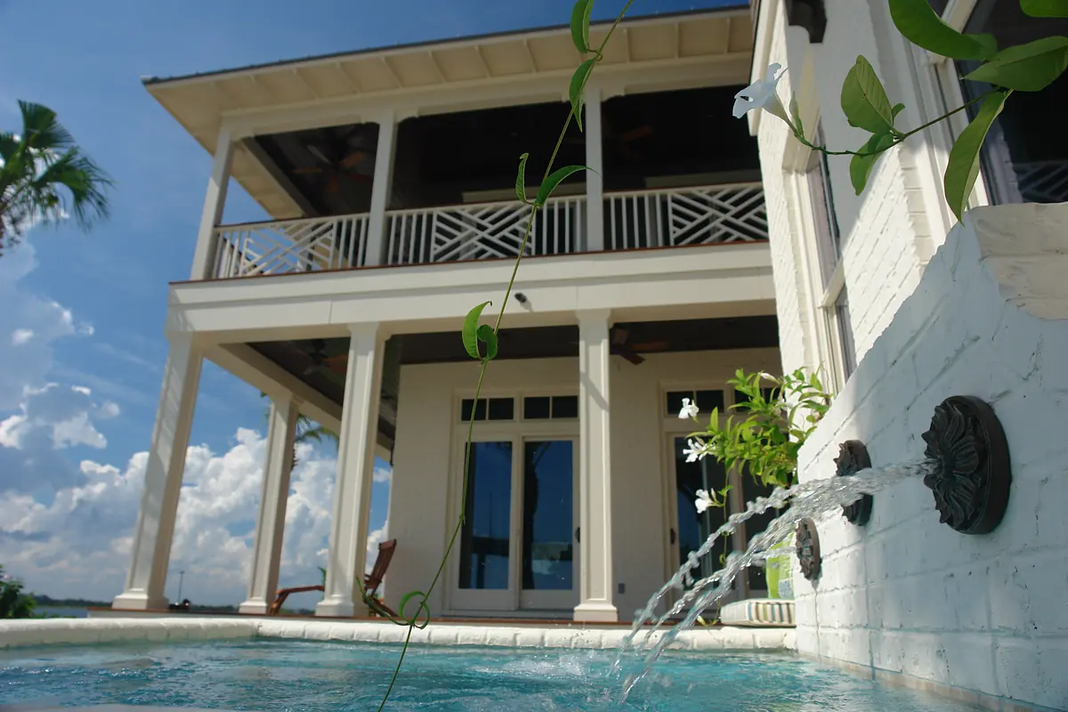 Exterior view with pool, two-story house, porch, and potted plants.