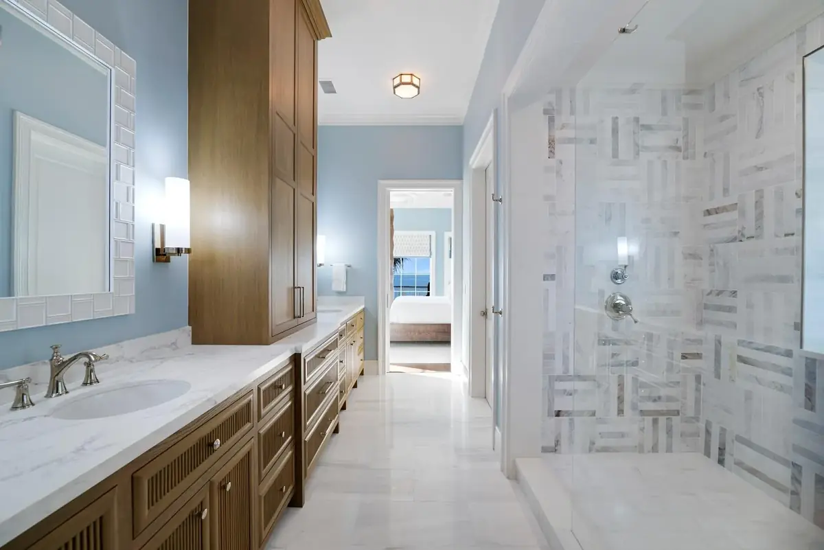 Bathroom with double vanity, marble countertop, large mirror, walk-in shower, and light blue walls.