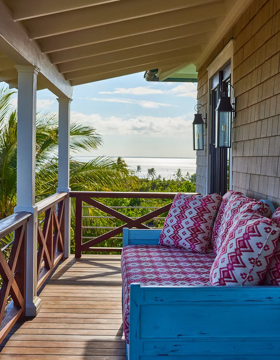 Deck with blue bench, patterned cushions, wooden planks, and ocean view
