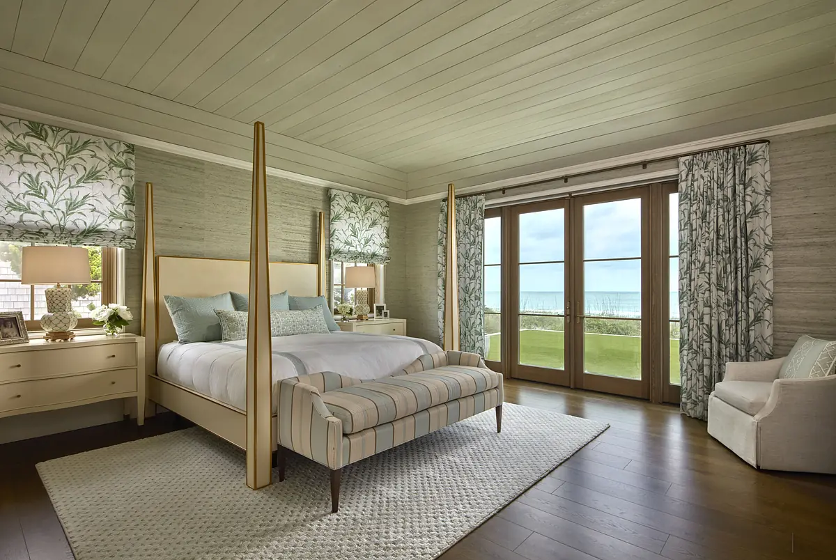 Bedroom with four-poster bed, striped bedding, floral curtains, nightstands, and hardwood floor.