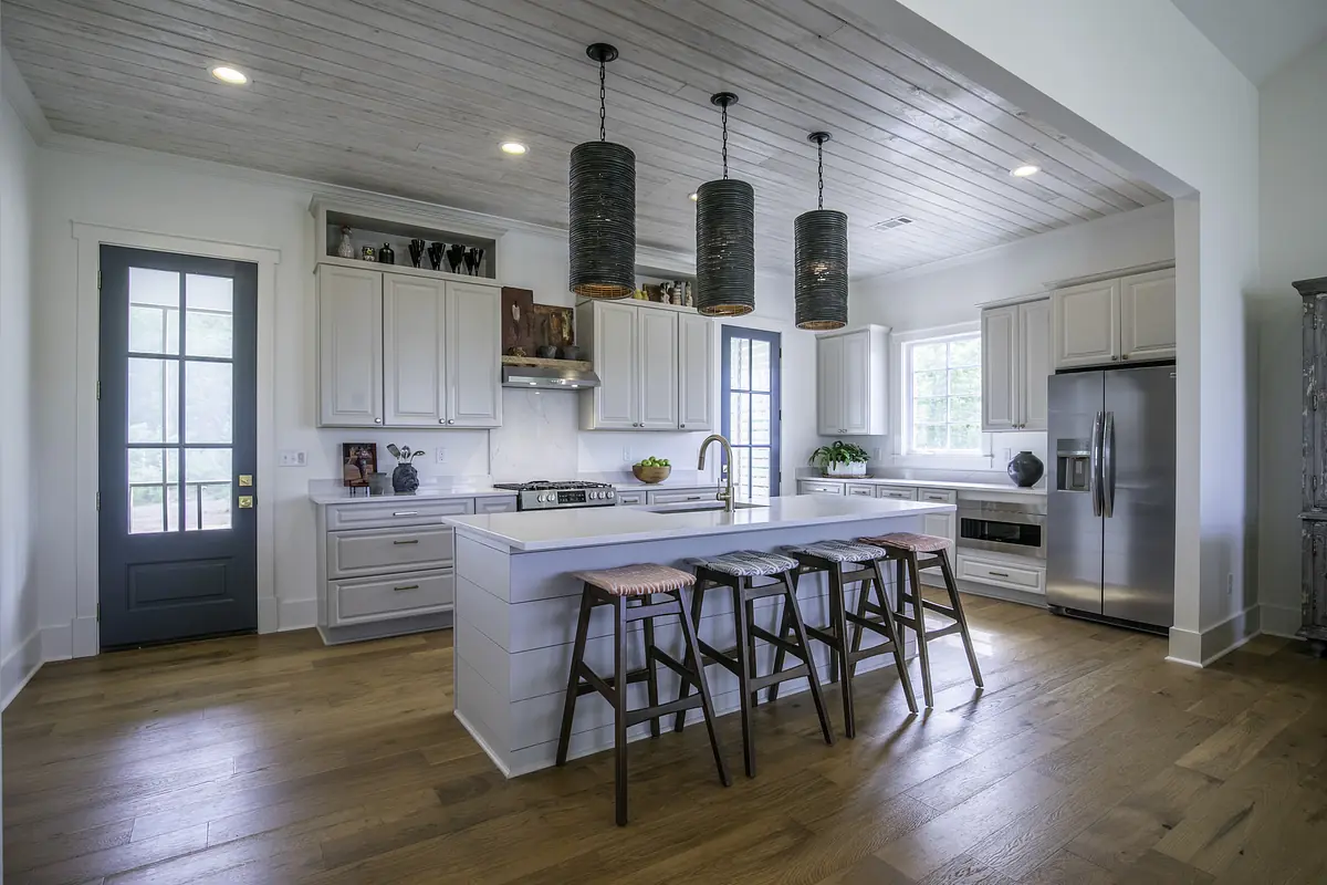 Kitchen with white cabinetry, large island, stainless steel appliances, and farmhouse sink.