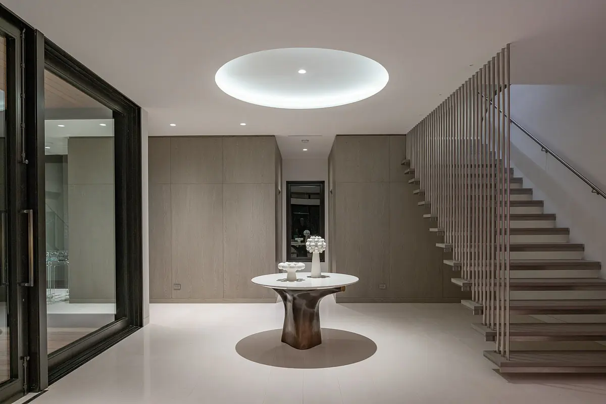 Foyer with round table, wood walls, staircase, and circular ceiling light.