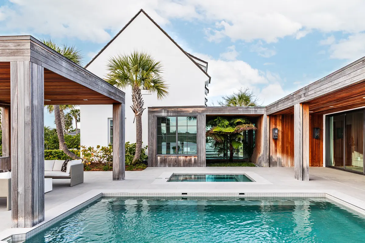 Exterior area with swimming pool, concrete deck, wooden overhangs, and palm trees surrounding a built-in spa.