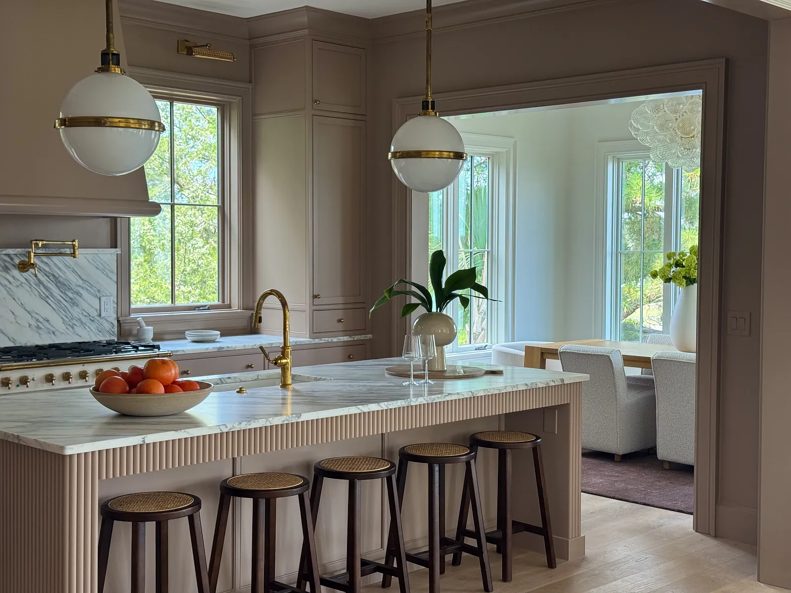 Kitchen with marble countertop island, bar stools, cooktop, large windows, and adjacent dining area.