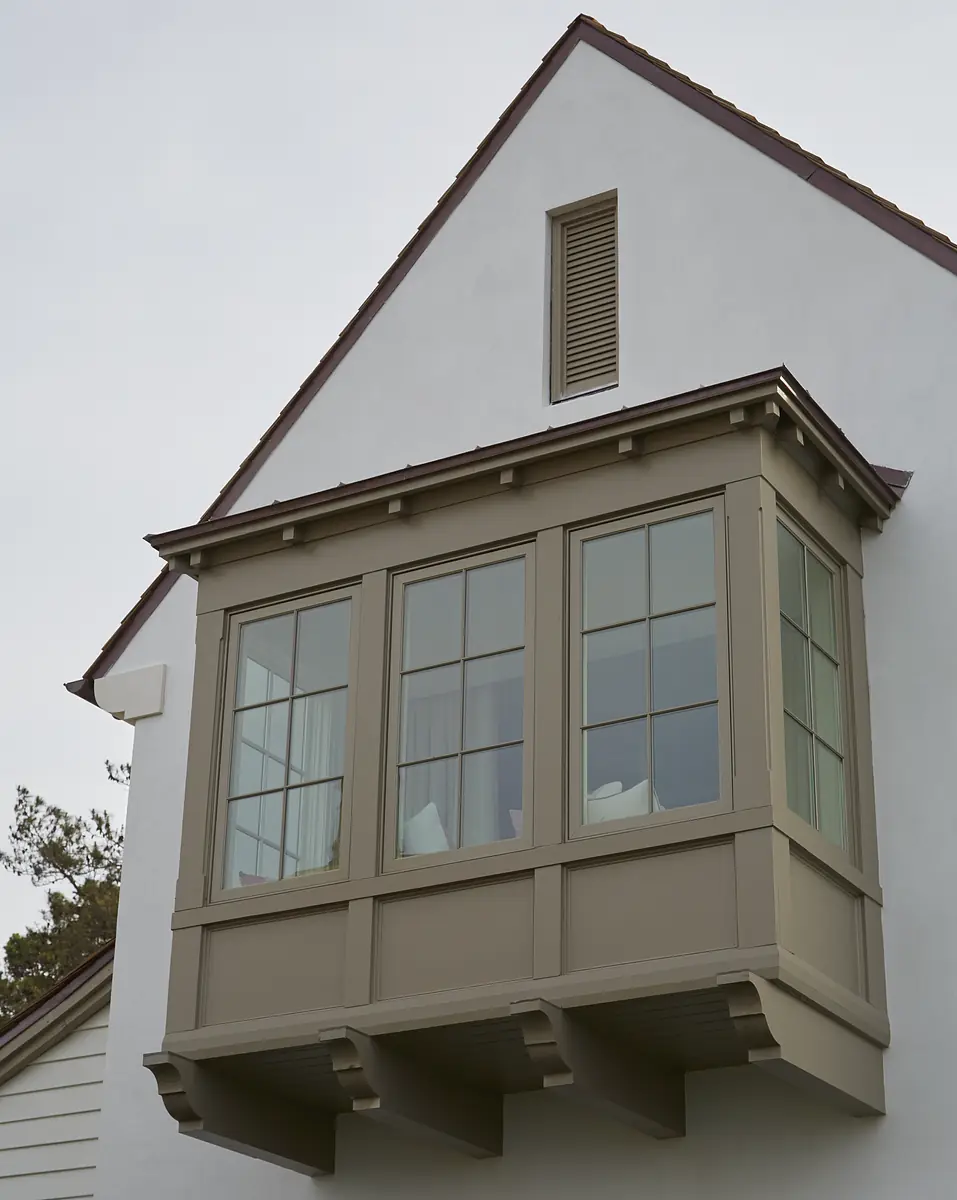 Exterior view with multi-pane window box, gray trim, white walls, and gabled roof.