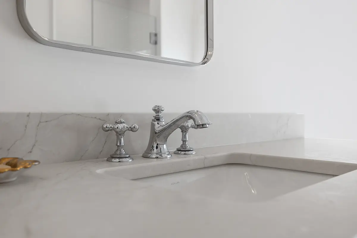 Bathroom with marble countertop, built-in sink, chrome faucet, and rectangular mirror.