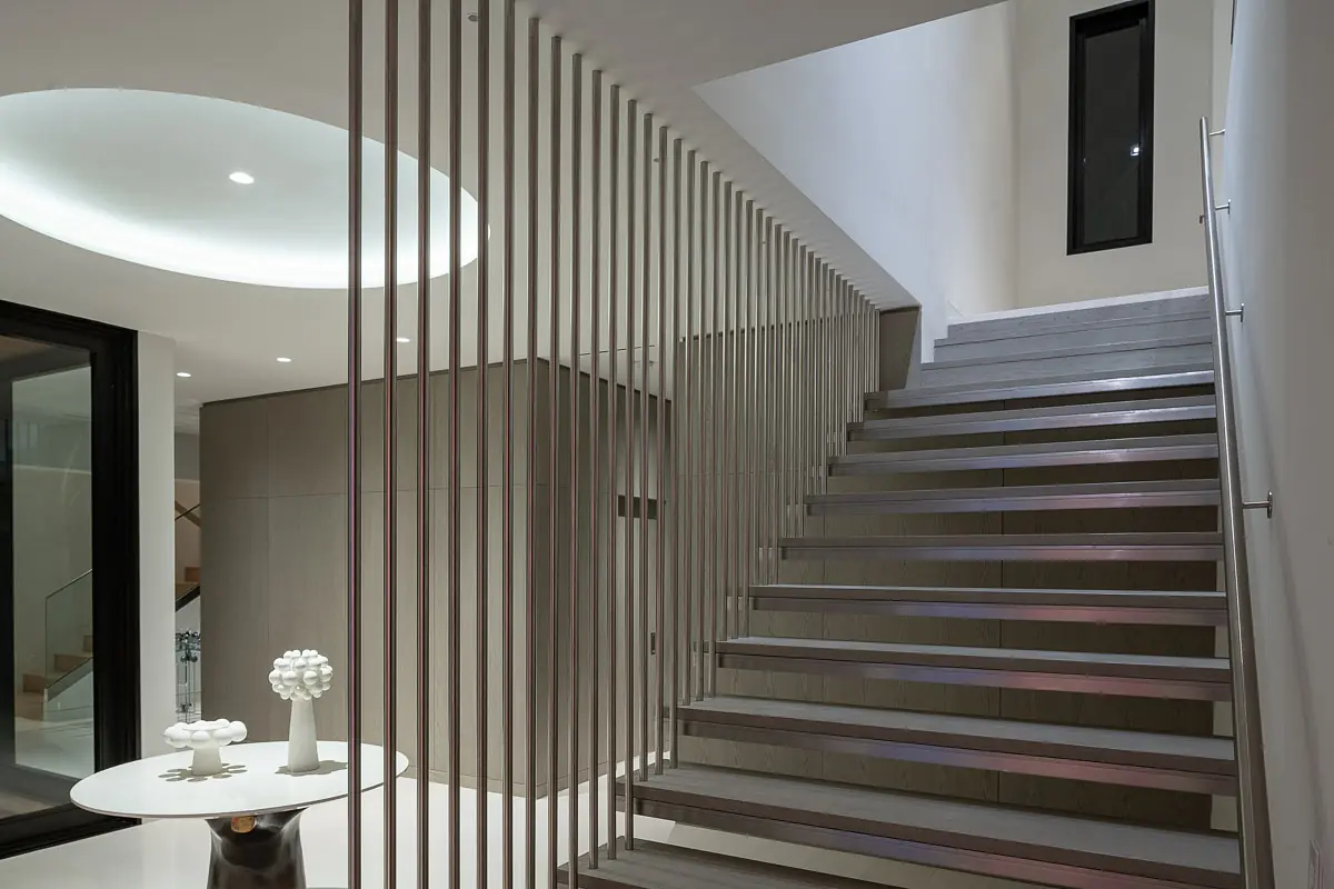 Foyer with wooden staircase, round table, decorative object, and high ceiling with recessed light