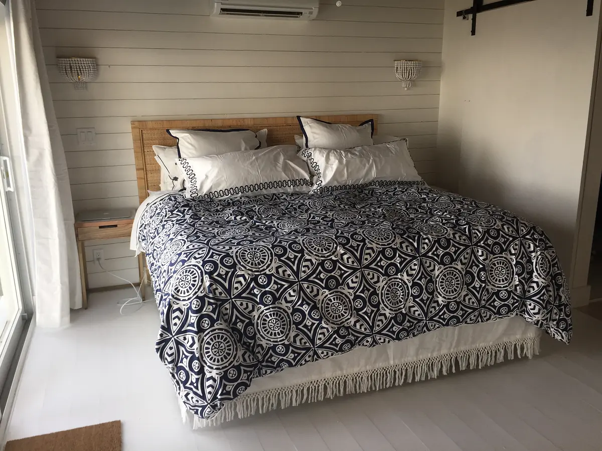Bedroom with king-sized bed, patterned quilt, nightstands, wall sconces, and sliding glass door