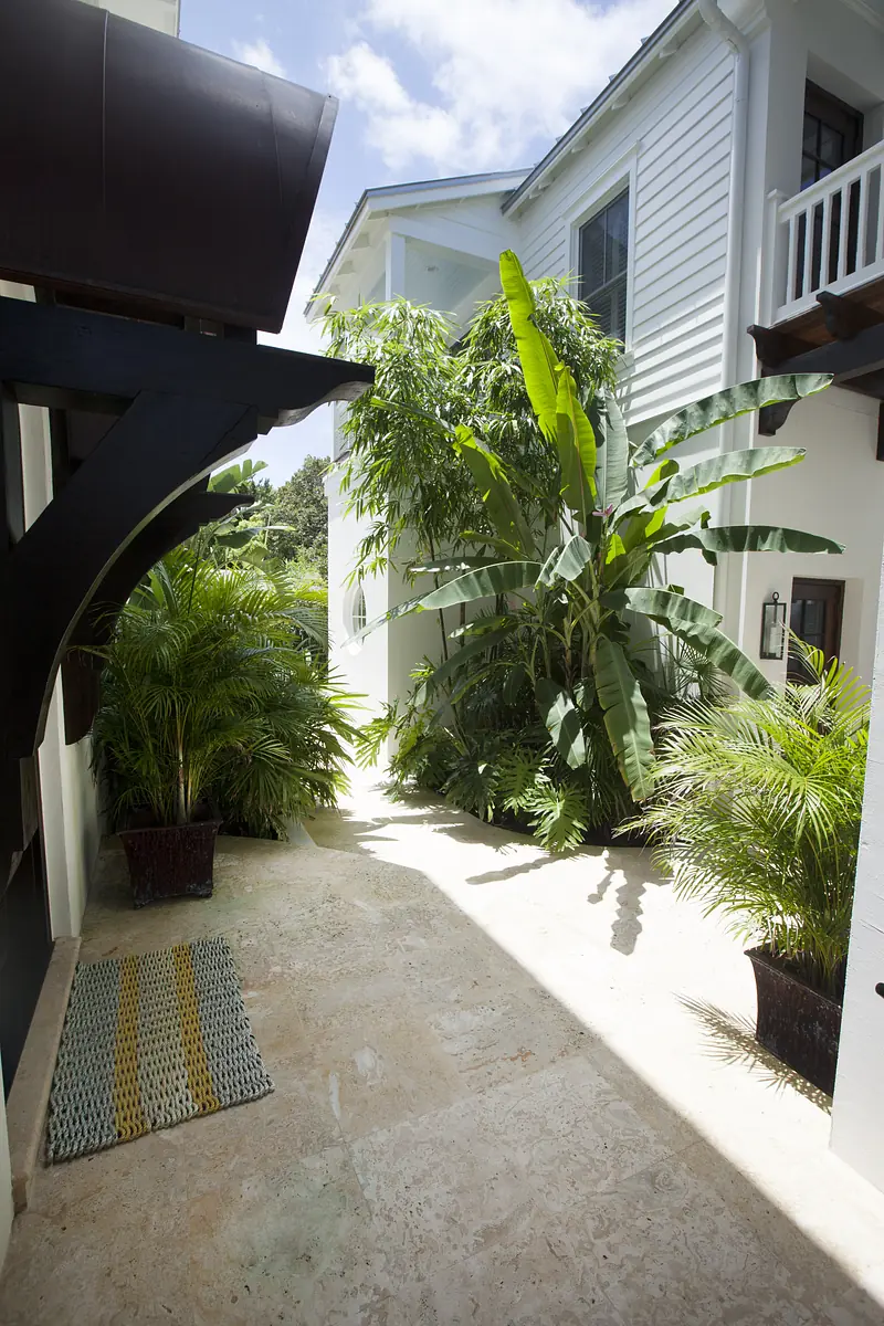 Garden area with stone flooring, potted plants, and banana trees lining the pathway.