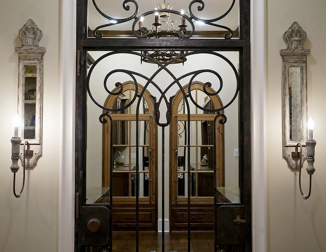 Foyer with wrought iron door, wall sconces, chandelier, arched mirrors, and wooden console table