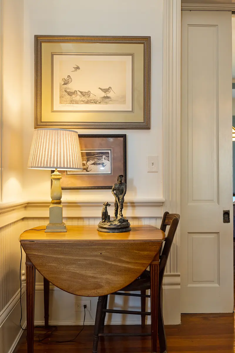 Small area with drop-leaf table, chair, sculptures, artwork, and paneled walls