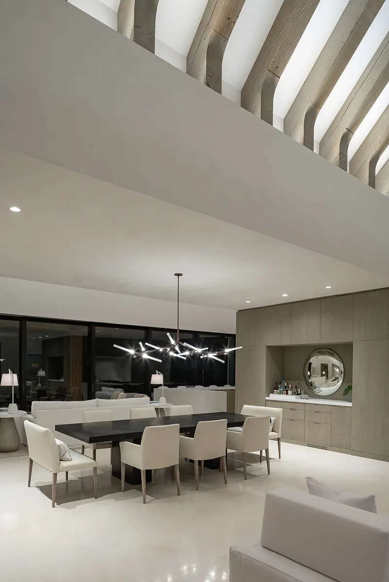 Dining room with rectangular table, eight chairs, large windows, built-in cabinet, and pendant lighting
