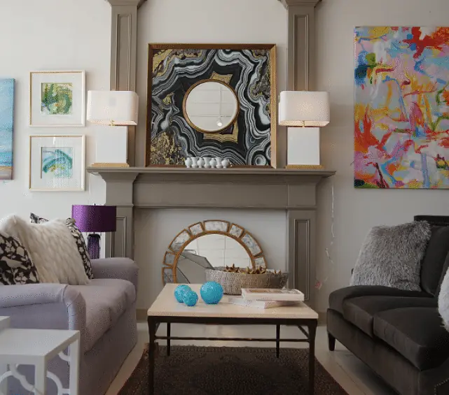 Living room with two sofas, coffee table, area rug, wall art, mirror, and fireplace with decor