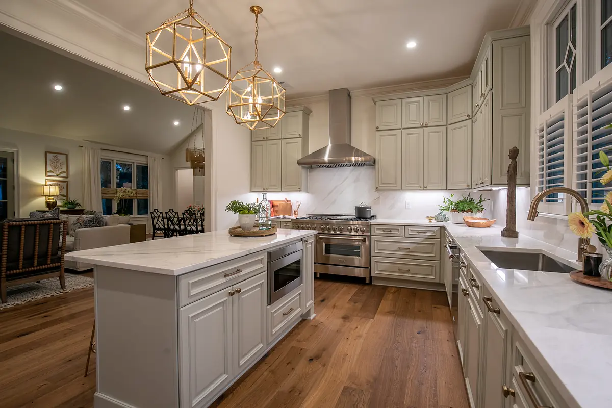 Kitchen with light gray cabinets, marble island, stainless steel appliances, and hardwood flooring.