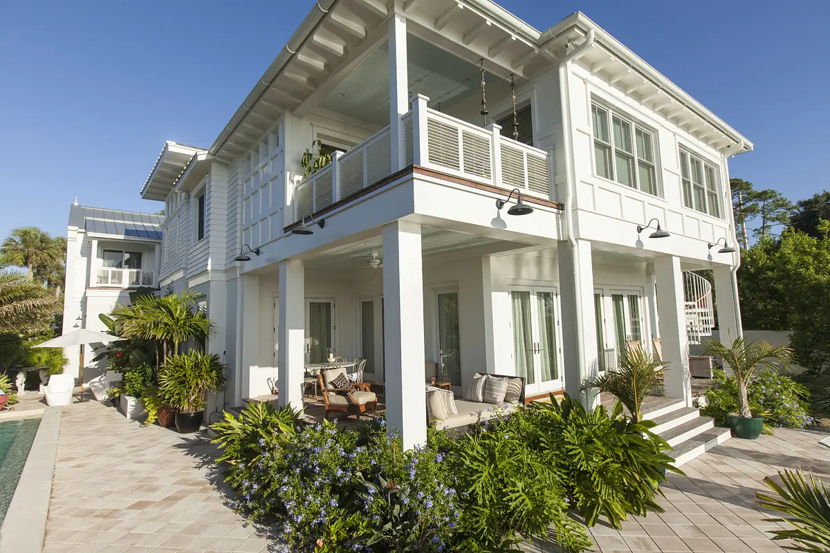 Exterior rear of a two-story house with porch, outdoor furniture, plants, and a pool.