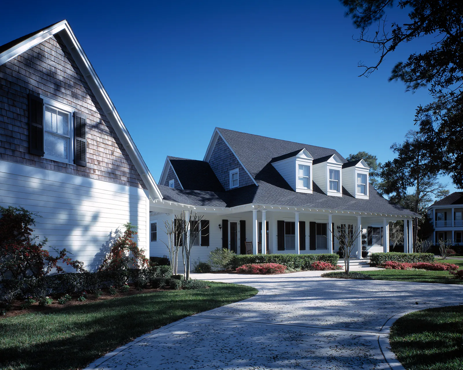 Exterior front view of a two-story house with gabled roof, white siding, porch, and landscaping.