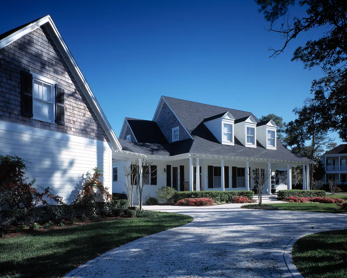 Exterior front view of a two-story house with gabled roof, white siding, porch, and landscaping.