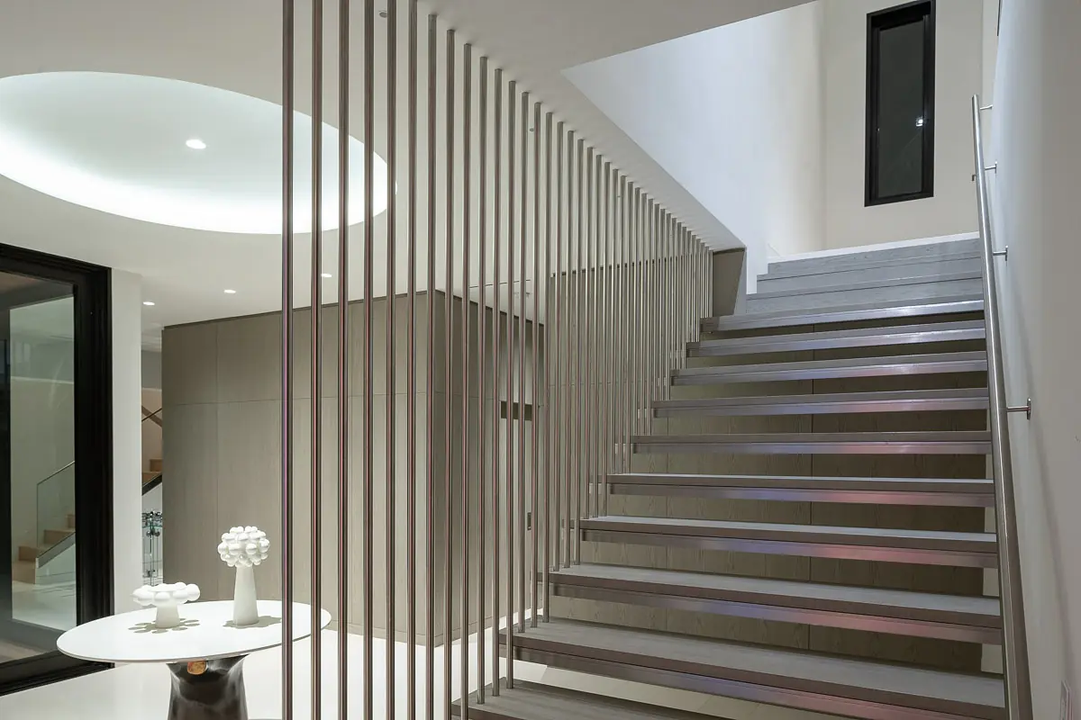 Interior space with staircase, round table, decorative object, and neutral walls with circular ceiling detail.