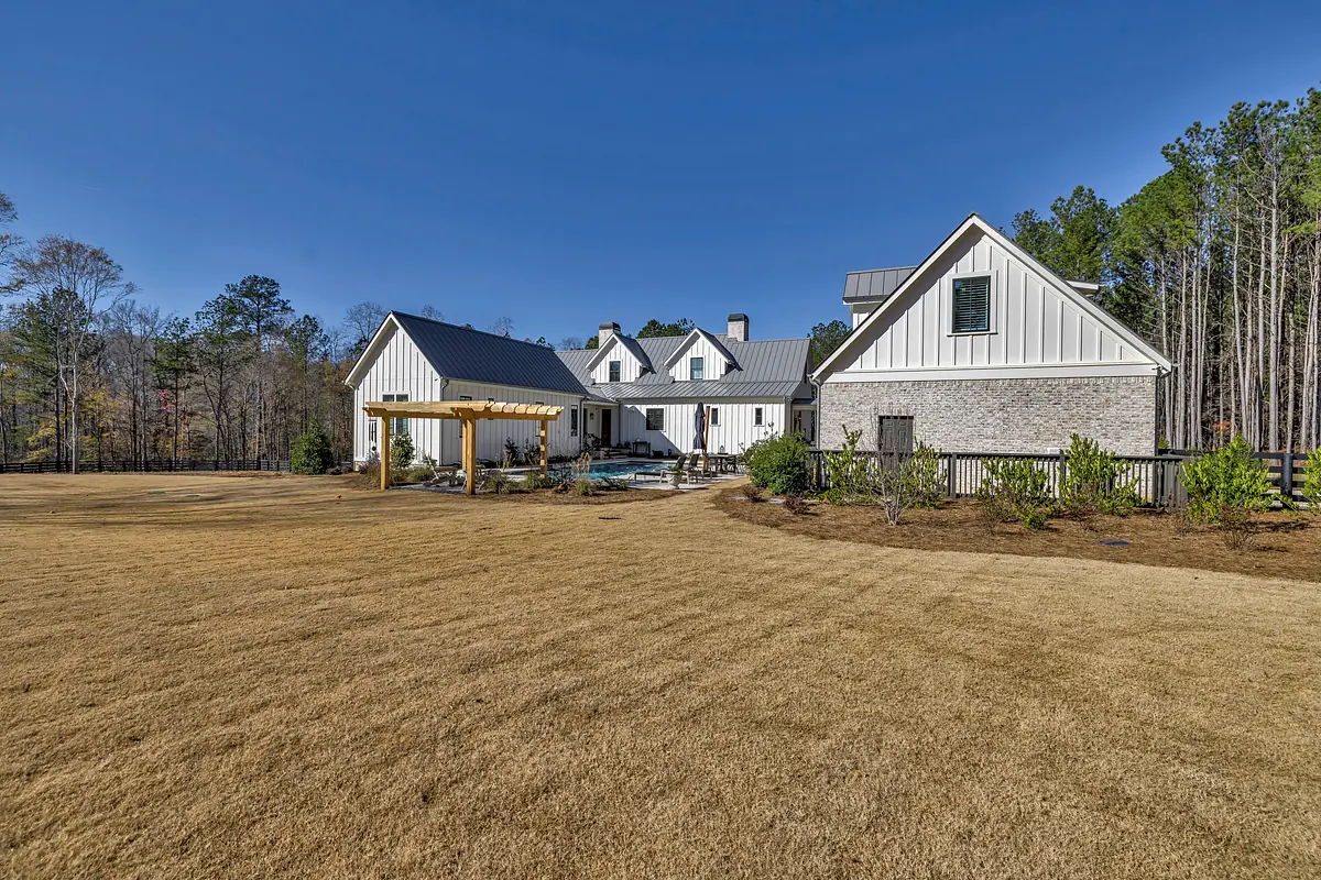 Exterior view of a house with mixed siding, brick, covered patio, and lawn.