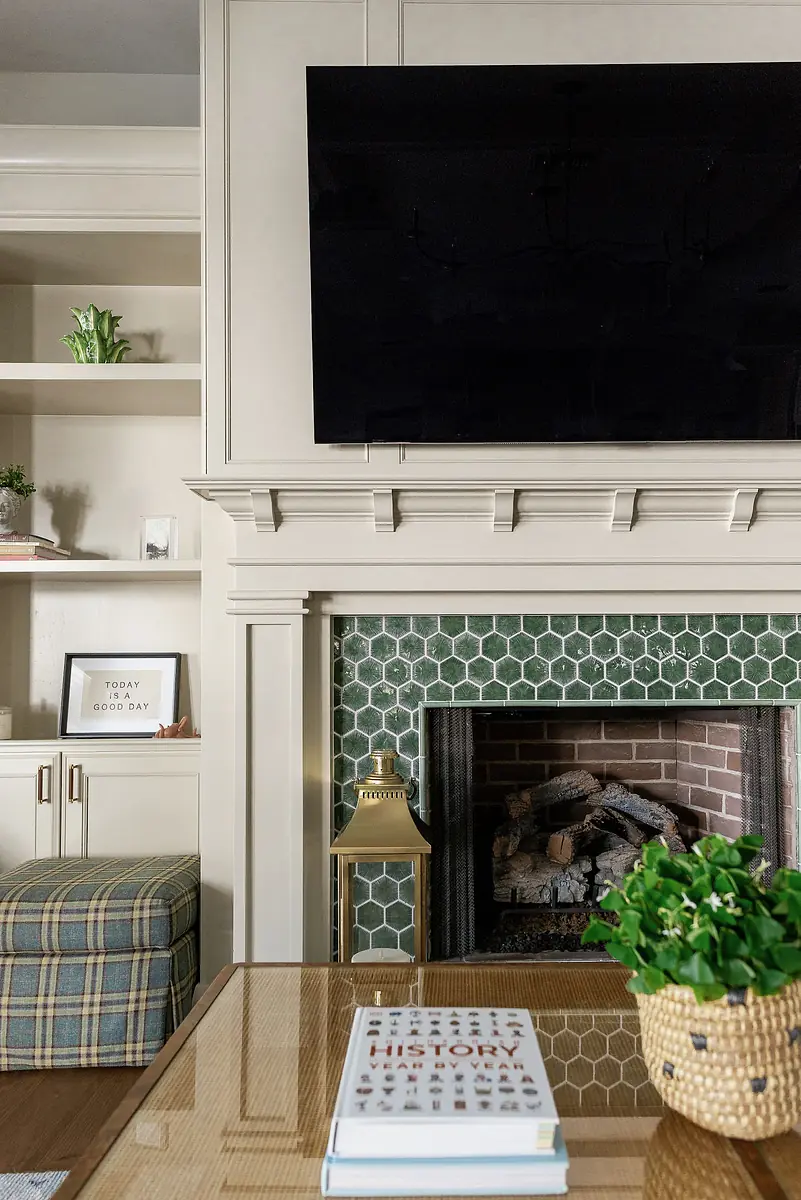 Living room with fireplace, mounted TV, coffee table, patterned chair, built-in shelves, and decorative plant.