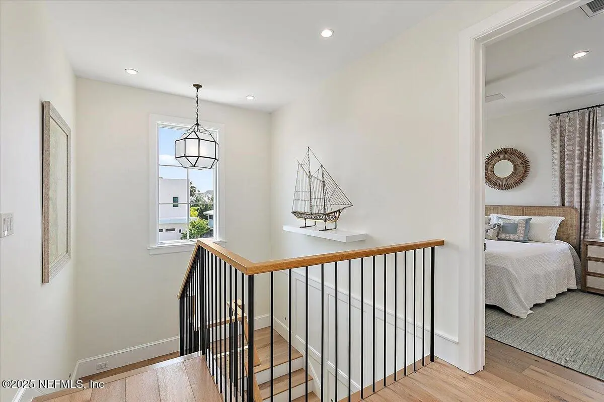 Hallway with wooden staircase, black railing, window, and decorative ship model on a ledge.