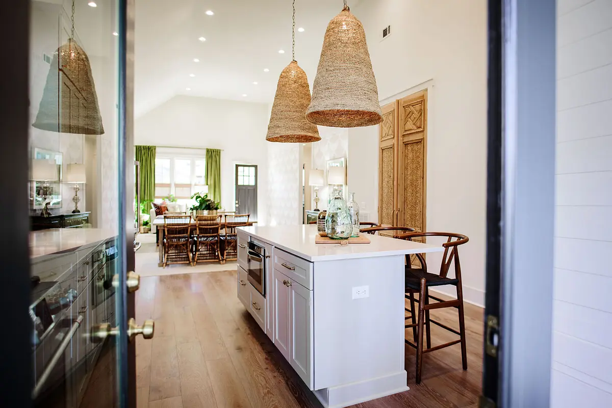 Kitchen with island, wood cabinetry, dining area, large windows, and pendant lights.