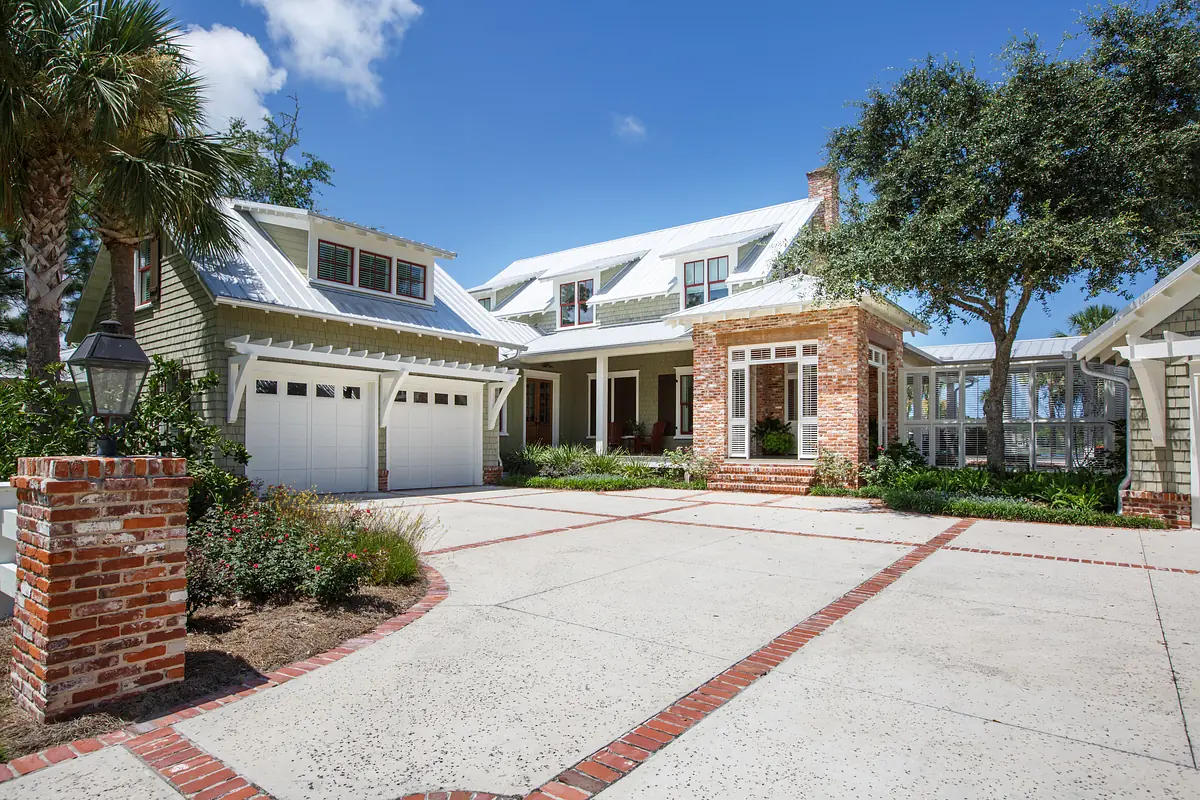 Exterior front of house with brick walkway, garage, landscaping, and gabled roof porch area.